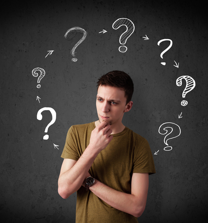 Thoughtful young man with drawn question marks circulating around his headの写真素材