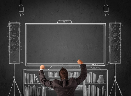 Young businessman standing and enjoying home cinema system sketched on a chalkboardの写真素材
