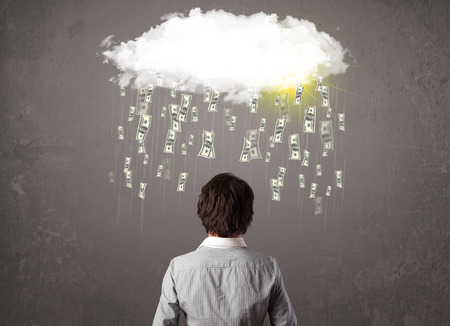 Business man in suit looking at cloud with falling money and sunの写真素材