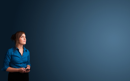 Pretty young woman standing and typing on her phone with copy spaceの写真素材