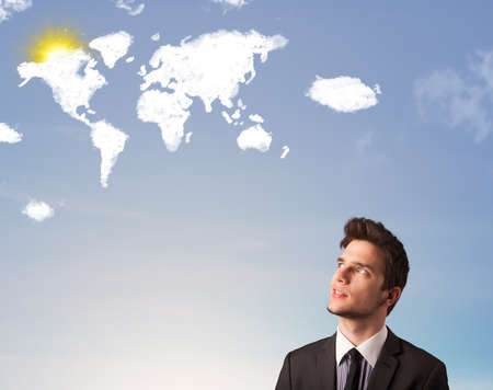 Businessman looking at world clouds and sun on blue skyの写真素材