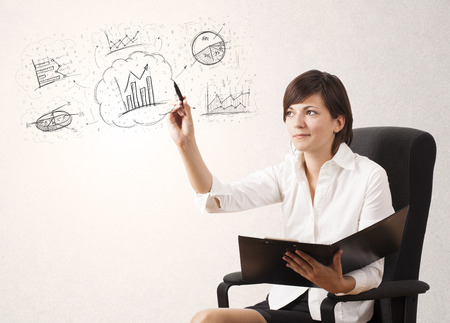 Young lady sketching financial chart icons and symbols on white backgroundの写真素材