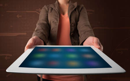 Young woman holding a white tablet with blurry apps