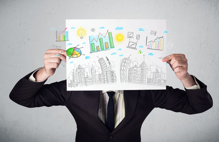 Businessman holding a paper in front of his head with charts and cityscape drawingの写真素材