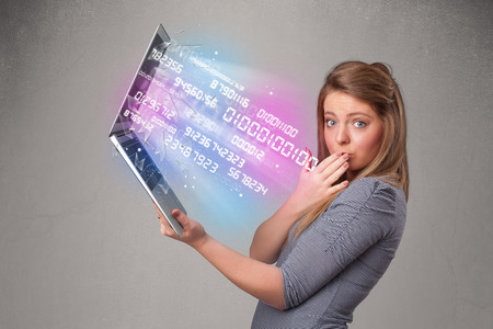 Attractive casual woman holding laptop with exploding data and numersの写真素材