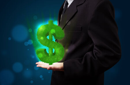 Young business man in suit presenting green glowing dollar signの写真素材