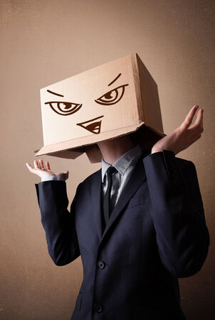 Businessman standing and gesturing with a cardboard box on his head with evil faceの写真素材