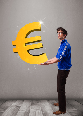 Good-looking young boy holding a big 3d gold euro signの写真素材