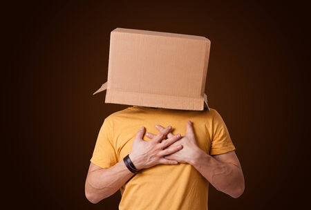 Young man standing and gesturing with a cardboard box on his head