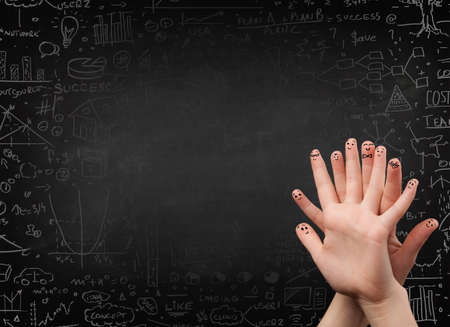 Happy finger smileys faces on hand with black chalkboard in backgroundの写真素材