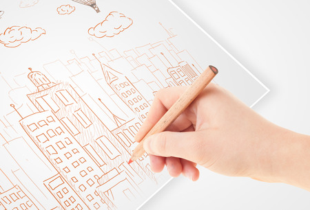 A person drawing sketch of a city with balloons and clouds on a plain paper
の写真素材