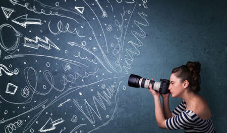 Photographer girl shooting images while energetic hand drawn lines and doodles come out of the cameraの写真素材