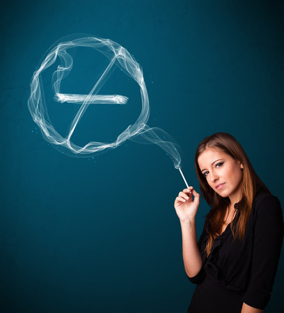 Pretty young lady smoking unheathy cigarette with no smoking signの写真素材
