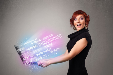 Attractive casual woman holding laptop with exploding data and numersの写真素材