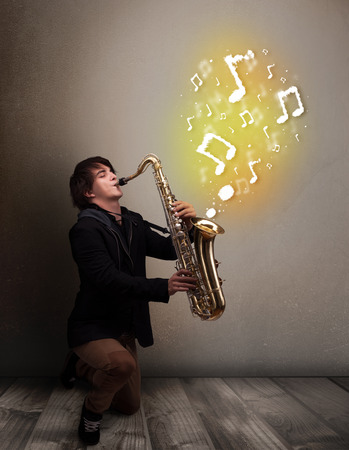 Handsome young musician playing on saxophone with musical notesの写真素材