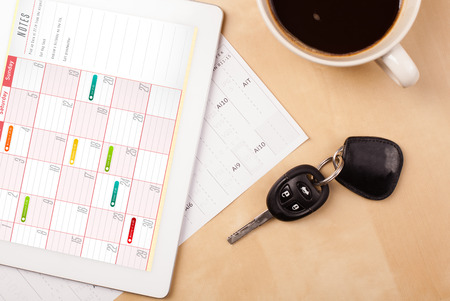 Workplace with tablet pc showing calendar and a cup of coffee on a wooden work table close-upの写真素材