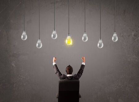 Businness guy in front of bright idea light bulbs conceptの写真素材