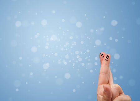 Happy finger smileys faces on hand with empty blue bokeh backgroundの写真素材