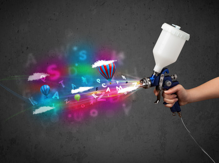 Worker with airbrush and colorful abstract clouds and balloons conceptの写真素材