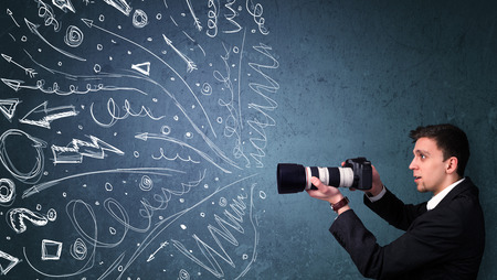 Photographer boy shooting images while energetic hand drawn lines and doodles come out of the cameraの写真素材