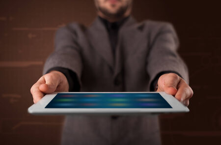 Young businessman holding a white modern tablet with blurry appsの写真素材