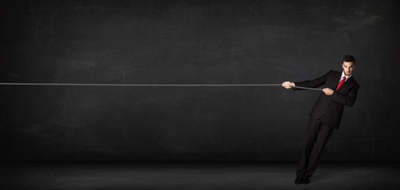 Businessman pulling rope on grey background conceptの写真素材