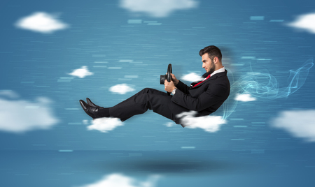 Funny racedriver young man driving between clouds concept on blue backgroundの写真素材
