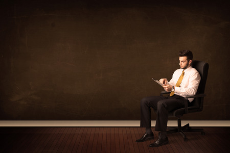 Businessman holding high tech tablet on brown background with copyspaceの写真素材