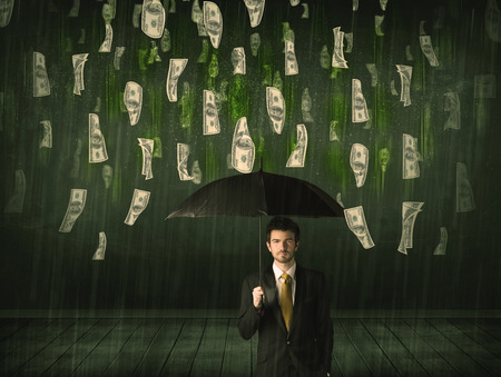 Businessman standing with umbrella in dollar bill rain concept on backgroundの写真素材