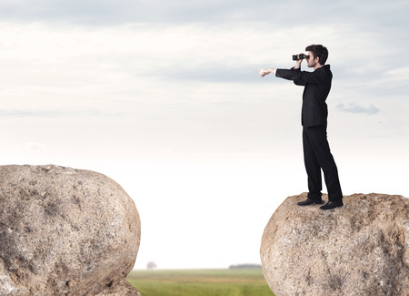 Young businessman standing on edge of rock mountainの写真素材