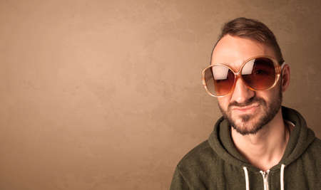 Portrait of a young pretty man with sunglasses and copyspace on brown backgroundの写真素材