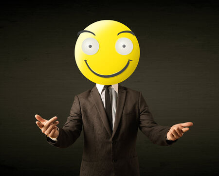 Funny businessman wears yellow smiley faceの写真素材