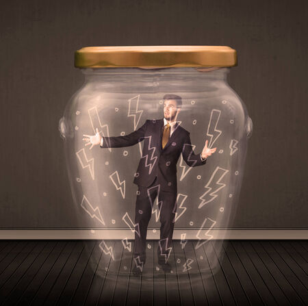 Businessman inside a glass jar with lightning drawings concept on backgroundの写真素材