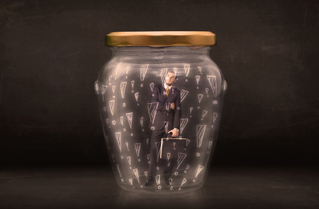 Business man trapped in jar with exclamation marks concept on bakcgroundの写真素材