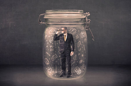 Business man captured in glass jar with hand drawn media icons concept on backgroundの写真素材