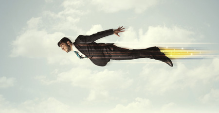Happy business man flying fast on the sky between clouds conceptの写真素材