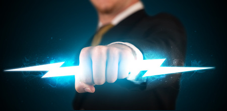 Business man holding glowing lightning bolt in his hands conceptの写真素材
