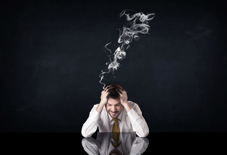 Young depressed businessman sitting with smoking headの写真素材