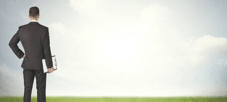 Businessman from the back in front of an empty meadowの写真素材