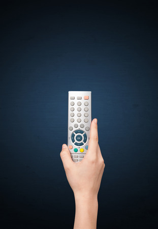 Hand holding a remote control on blue backgroundの写真素材
