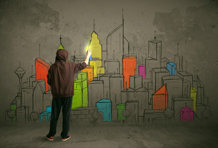 Young urban painter drawing colorful city  on the wallの写真素材