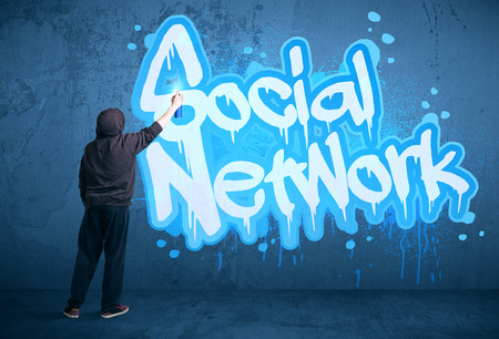 Young urban painter drawing a social network subtitle on the wallの写真素材