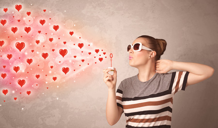 Pretty young girl blowing valentine red heart symbolsの写真素材