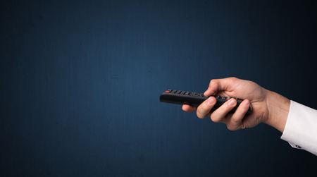 Hand holding a remote control on blue backgroundの写真素材