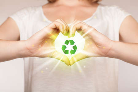 Hands creating a form with green recycling sign in the centerの写真素材