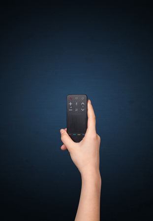 Hand holding a remote control on blue backgroundの写真素材