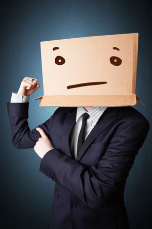 Businessman standing and gesturing with a cardboard box on his head with straight faceの写真素材