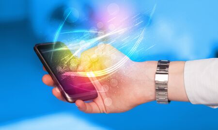 Hand holding smart phone with abstract glowing lines concept