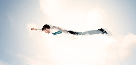 Business man flying like a superhero in clouds on the sky conceptの写真素材