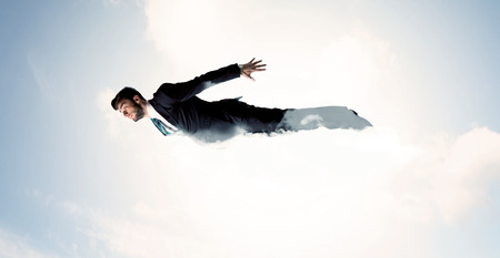 Business man flying like a superhero in clouds on the sky conceptの写真素材